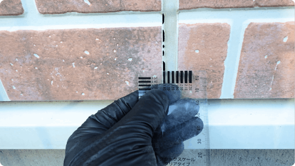 外壁のシーリングにクラックスケールを当てている様子